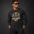 Athletisches männliches Model mit Sonnenbrille trägt ein schwarzes Badger 47 Longsleeve mit Vintage-Grafik und schwarze Hose vor anthrazitfarbenem Studiohintergrund.