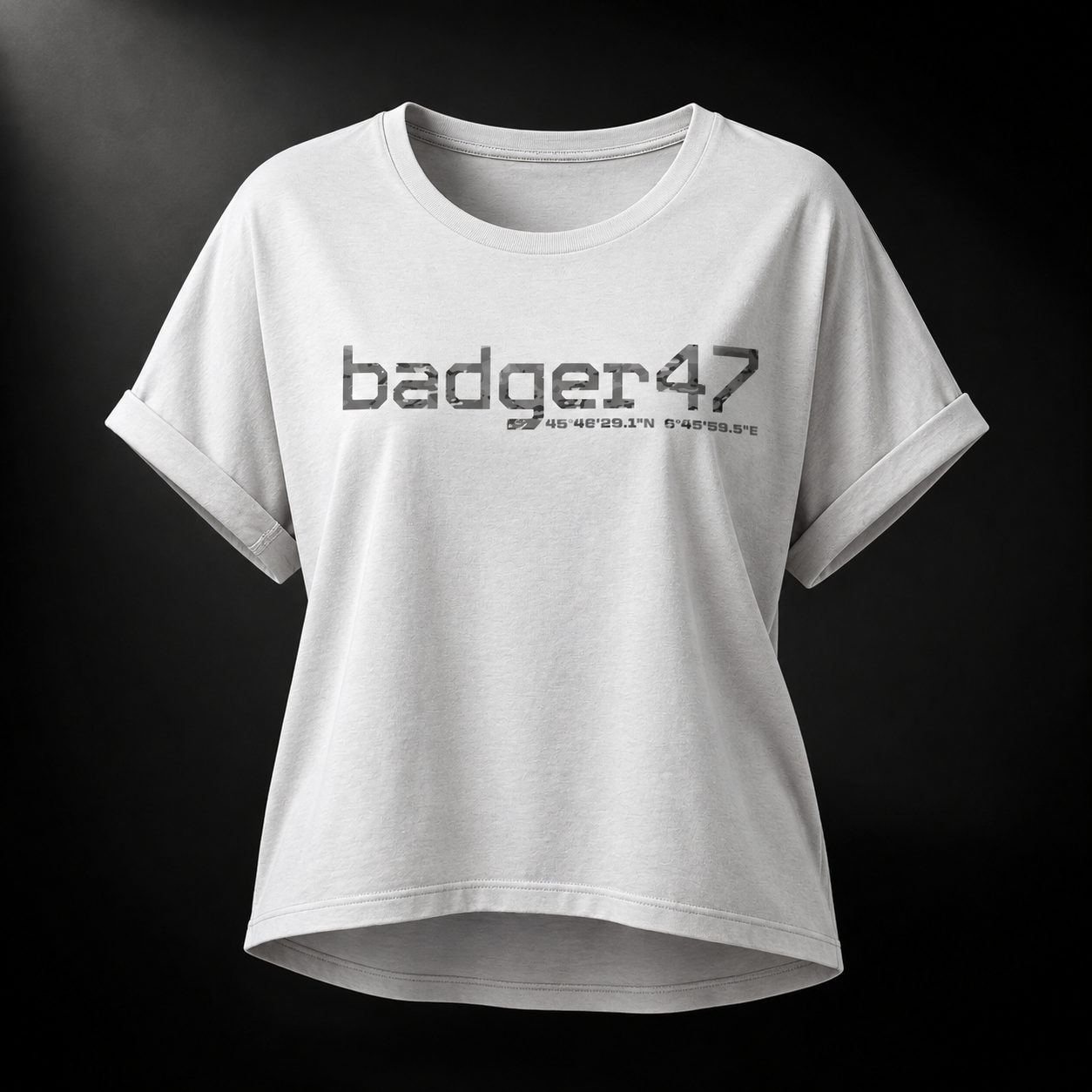 Weißes Badger 47 Multicam Grau Damen-T-Shirt mit weitem Schnitt, gerollten Ärmeln, längerem Rückensaum und grauem Camouflage-Logo im Studiolicht
