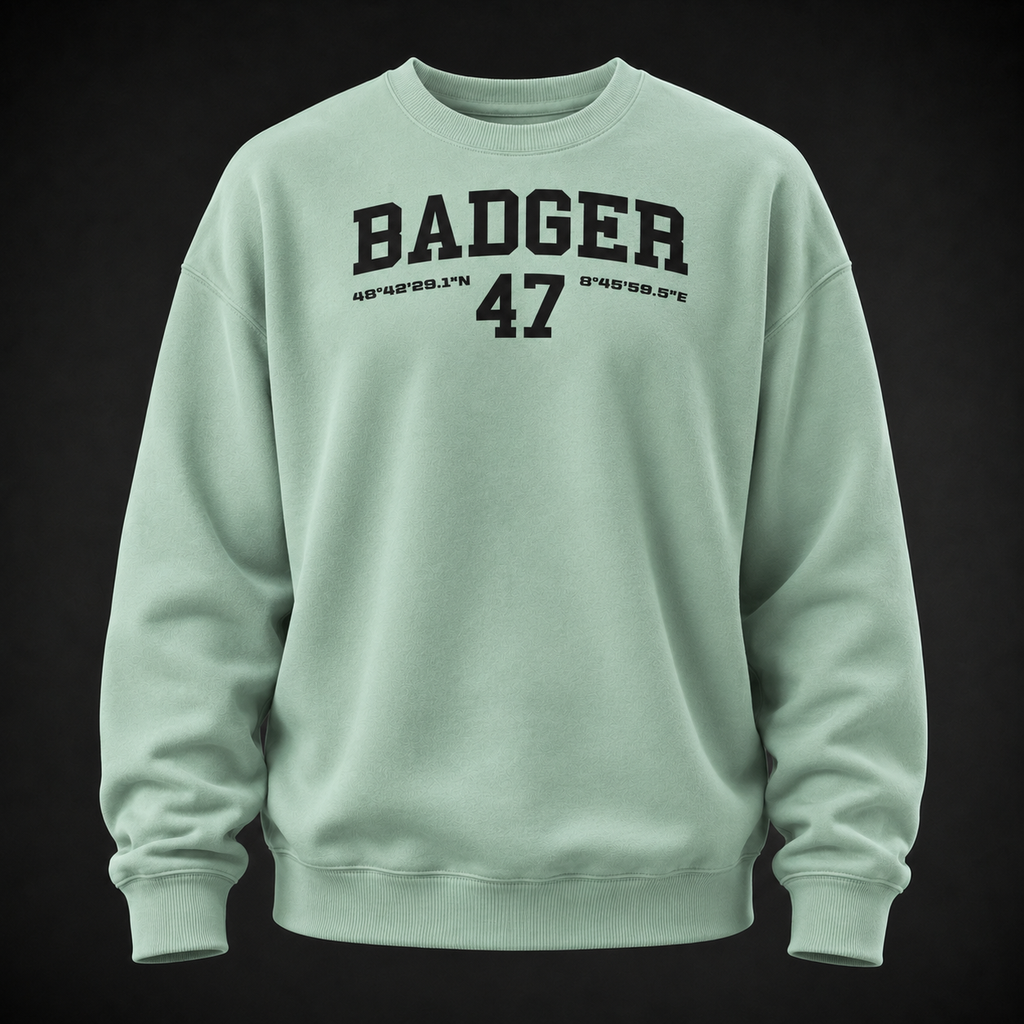 Oversize Sweatshirt in Misty Jade mit schwarzem BADGER-47-Print, frontal als Ghost-Mannequin vor dunklem Studiohintergrund dargestellt.