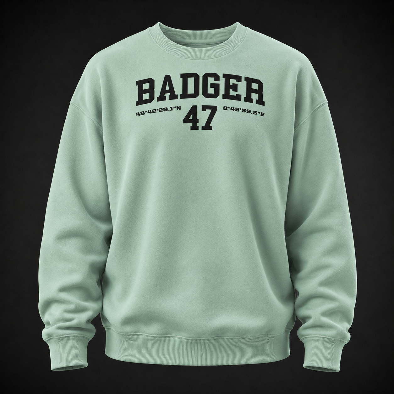 Oversize Sweatshirt in Misty Jade mit schwarzem BADGER-47-Print, frontal als Ghost-Mannequin vor dunklem Studiohintergrund dargestellt.
