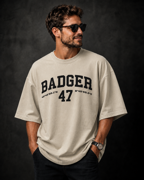 Beiges Oversized Herren T-Shirt mit schwarzem BADGER 47 Print und Koordinaten auf der Brust
