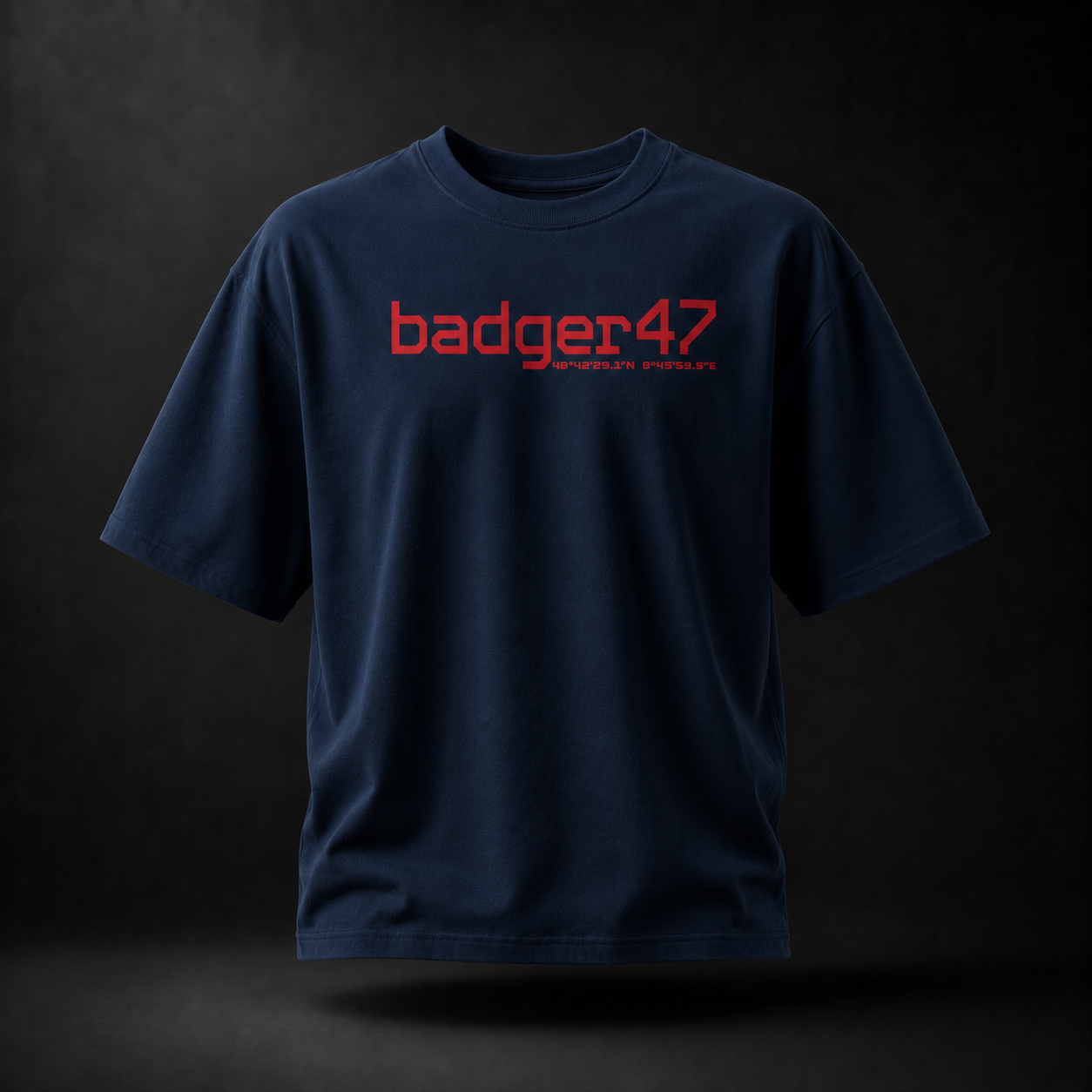 Dunkelblaues Badger 47 Strive Oversized T-Shirt mit rotem Logo-Print auf der Vorderseite im dramatischen Studiolicht
