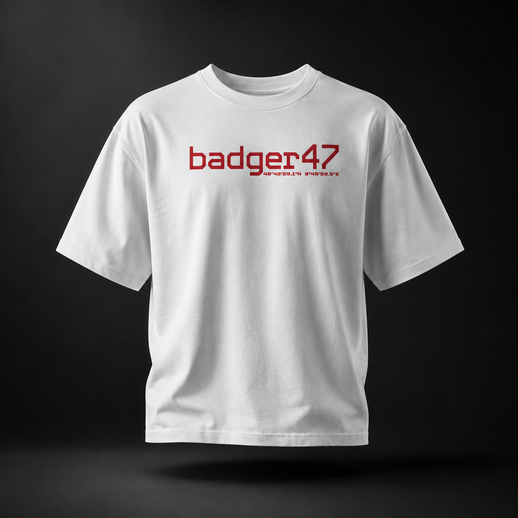 Weißes Badger 47 Strive Oversized T-Shirt mit rotem Logo-Print auf der Vorderseite, schwebend im dunklen Studiolicht

