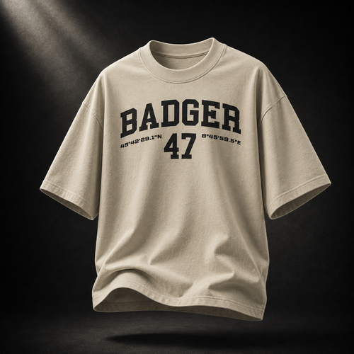 Beigefarbenes Badger 47 Varsity Oversized T-Shirt in Stone mit schwarzem College-Print im dramatischen Studiolicht
