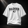Weißes Badger 47 Varsity Oversized T-Shirt mit schwarzem College-Print, schwebend vor dunklem Studiohintergrund
