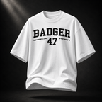 Weißes Badger 47 Varsity Oversized T-Shirt mit schwarzem College-Print, schwebend vor dunklem Studiohintergrund
