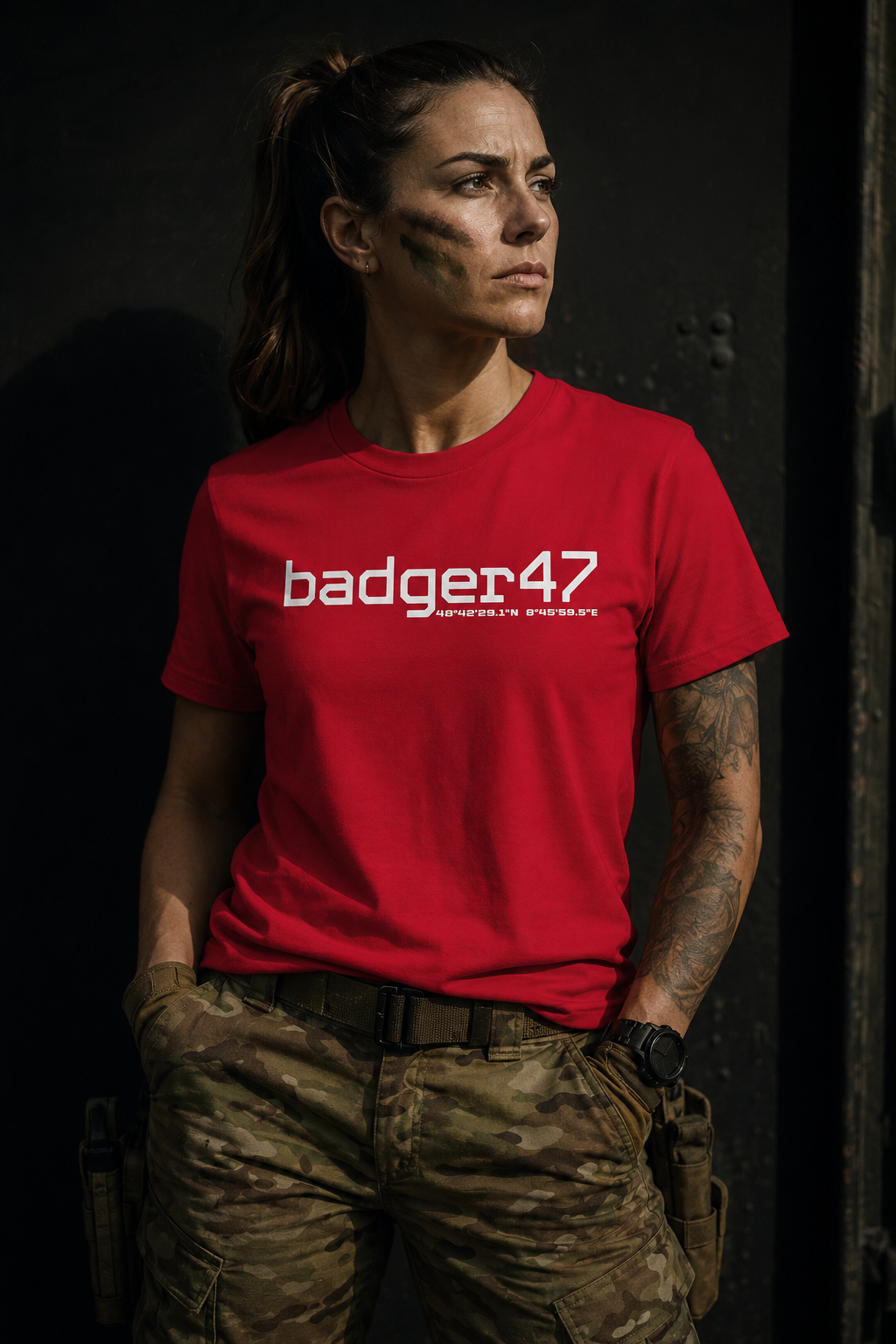 Frau im militärisch inspirierten Look trägt ein rotes badger47 Bio T-Shirt mit weißem Coordinates-Print

