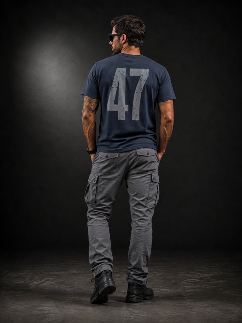 Rückansicht eines männlichen Models im Badger47 Distressed Organic T-Shirt in India Ink Grey mit großem grauem 47-Backprint, kombiniert mit grauer Cargo-Hose und schwarzen Boots vor dunklem Studiohintergrund.