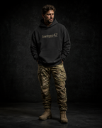 BADGER47 FIELD Boxcut Hoodie in Black mit Multicam-Logo, getragen mit Multicam-Hose im dunklen Studio
