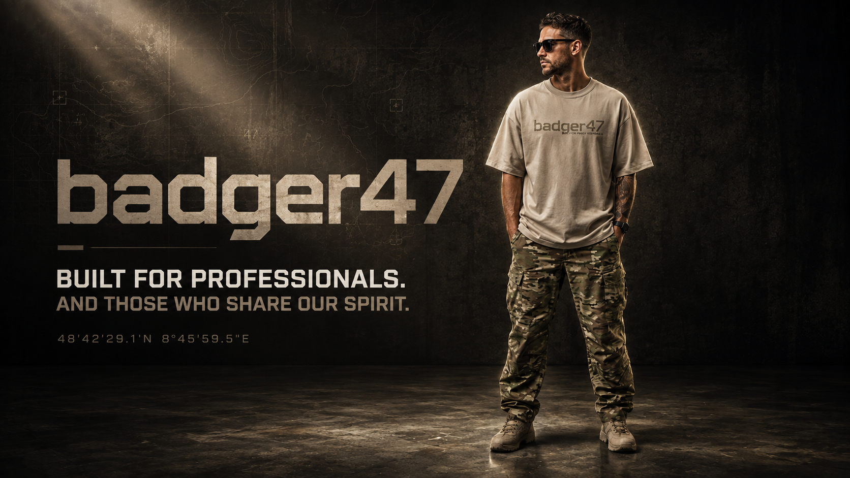 Mann im beige oversized badger47 T-Shirt und Multicam-Cargohose vor dunklem, taktisch inszeniertem Hintergrund mit dem Claim „Built for Professionals. And Those Who Share Our Spirit.“