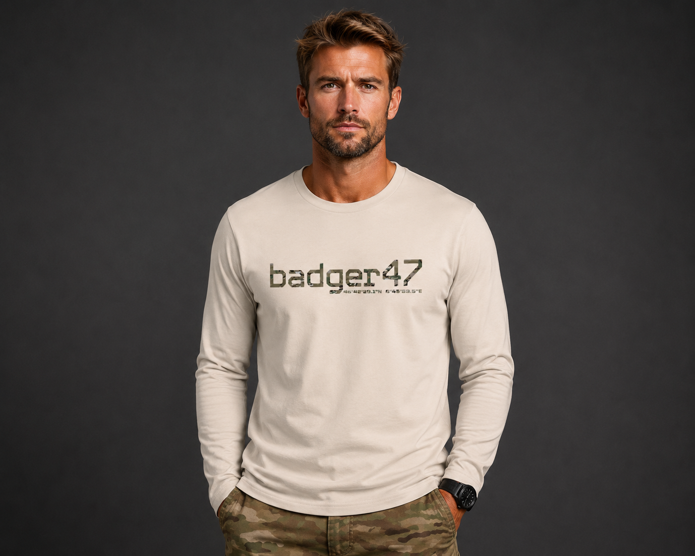 Dunkelblondes Männermodel mit badger47 Organic Longsleeve in Natural Raw und Multicam-Hose vor anthrazitfarbenem Studiohintergrund
