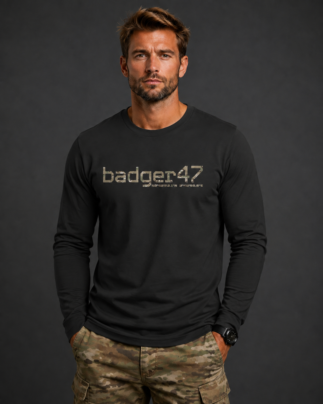 Dunkelblondes Männermodel mit schwarzem badger47 Organic Longsleeve und Multicam-Hose vor anthrazitfarbenem Studiohintergrund