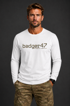 Dunkelblondes Männermodel mit weißem badger47 Organic Longsleeve und Multicam-Hose vor anthrazitfarbenem Studiohintergrund