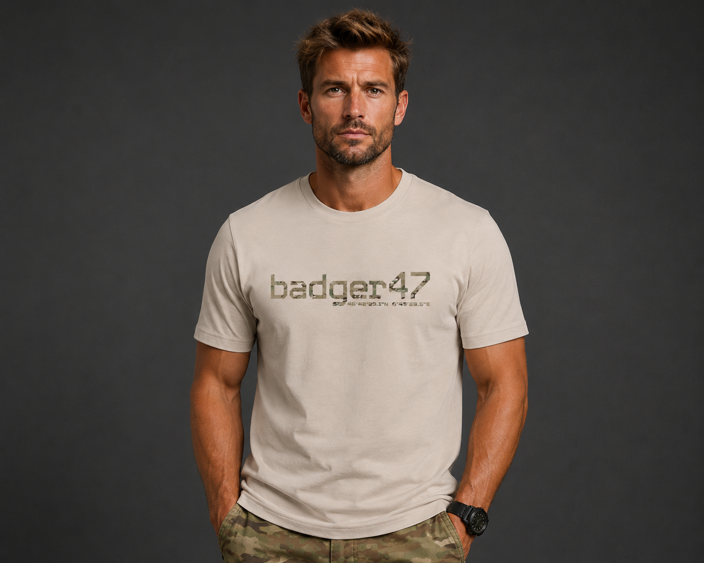 Dunkelblondes Männermodel mit badger47 Organic T-Shirt in Desert Dust und Multicam-Hose vor anthrazitfarbenem Studiohintergrund