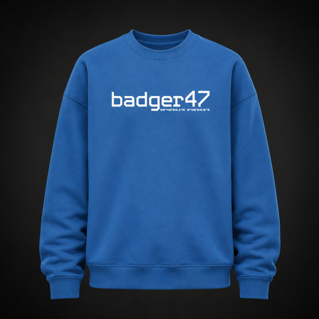 Oversize Sweatshirt in Mindful Blue mit weißem badger47-Frontprint und Koordinaten-Detail auf der Brust, frontal als Ghost-Mannequin vor dunklem Studiohintergrund dargestellt.