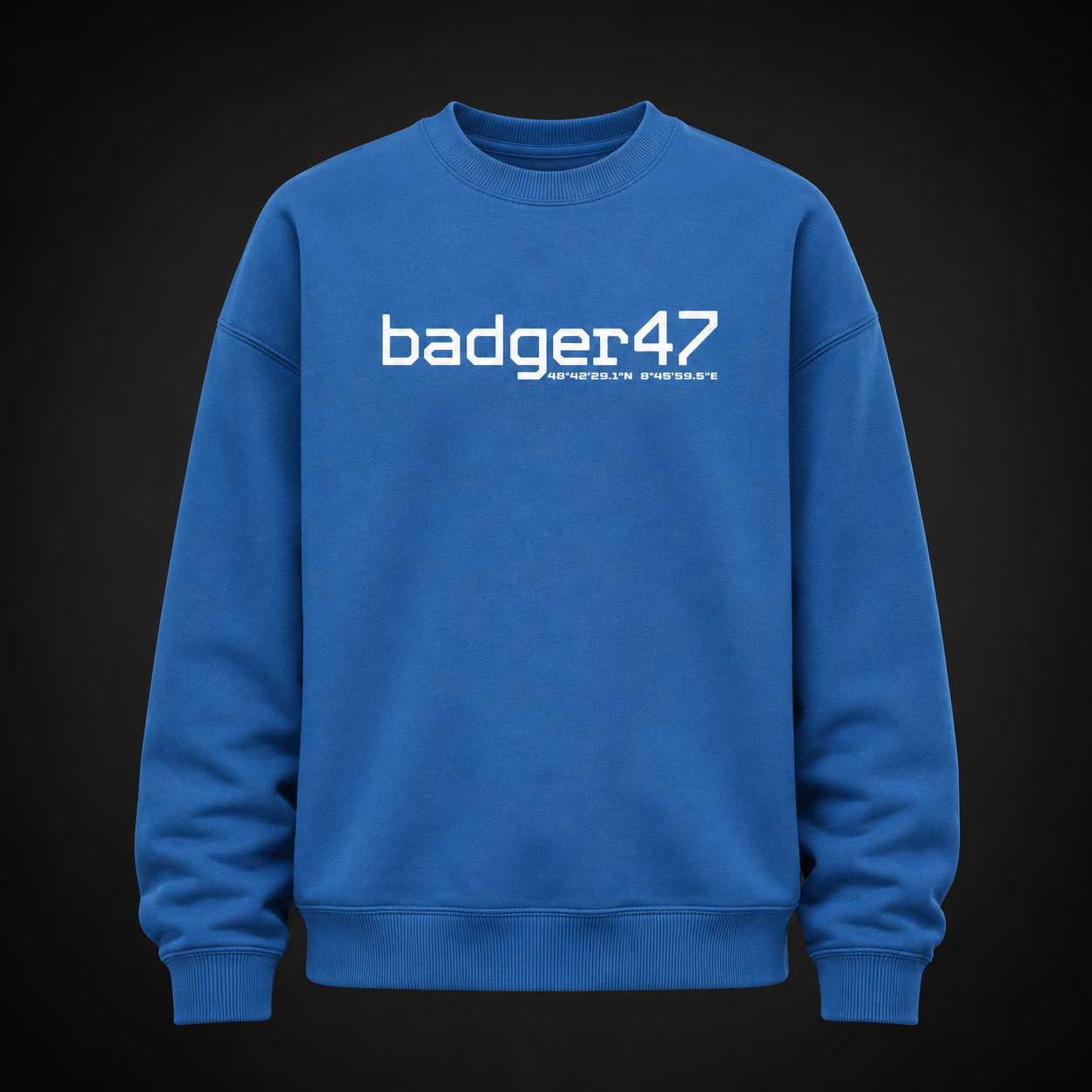 Oversize Sweatshirt in Mindful Blue mit weißem badger47-Frontprint und Koordinaten-Detail auf der Brust, frontal als Ghost-Mannequin vor dunklem Studiohintergrund dargestellt.