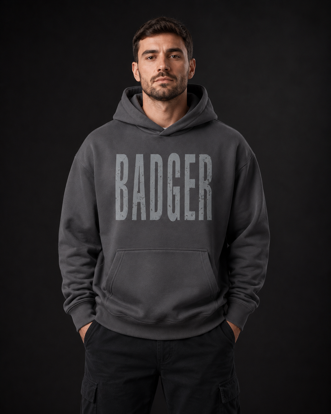 Männermodel trägt einen dunkelgrauen badger47 Oversized Hoodie mit großem BADGER-Print auf der Vorderseite
