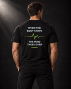 Rückansicht des schwarzen BADGER47 T-Shirts mit „When The Body Stops The Mind Takes Over“-Print und grüner Pulslinie.