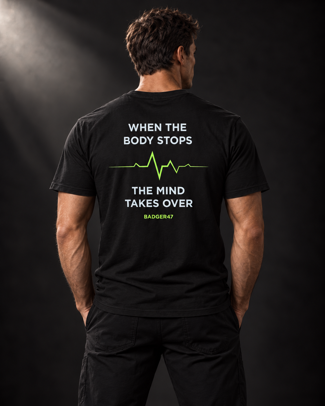 Rückansicht des schwarzen BADGER47 T-Shirts mit „When The Body Stops The Mind Takes Over“-Print und grüner Pulslinie.