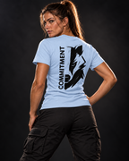 Athletische Frau in hellblauem T-Shirt mit schwarzem COMMITMENT Wolf-Print auf dem Rücken und schwarzer Cargo-Hose.